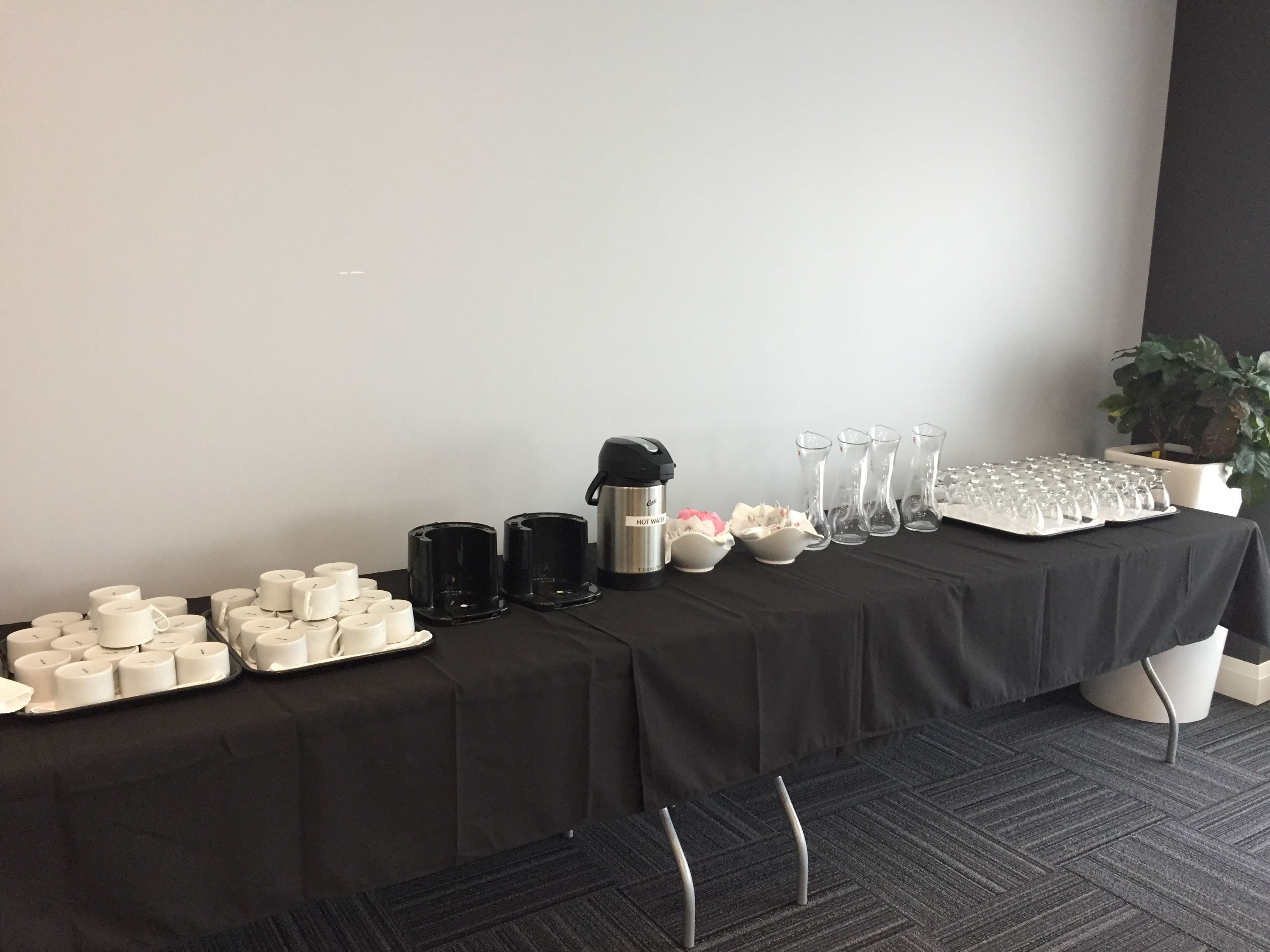A table with various items including candles, coffee makers, and glassware, likely set up for a gathering or event.
