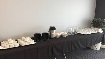 Taula amb diversos objectes, com ara espelmes, cafeteres i recipient de vidre, probablement preparada per a una reunió o esdeveniment.