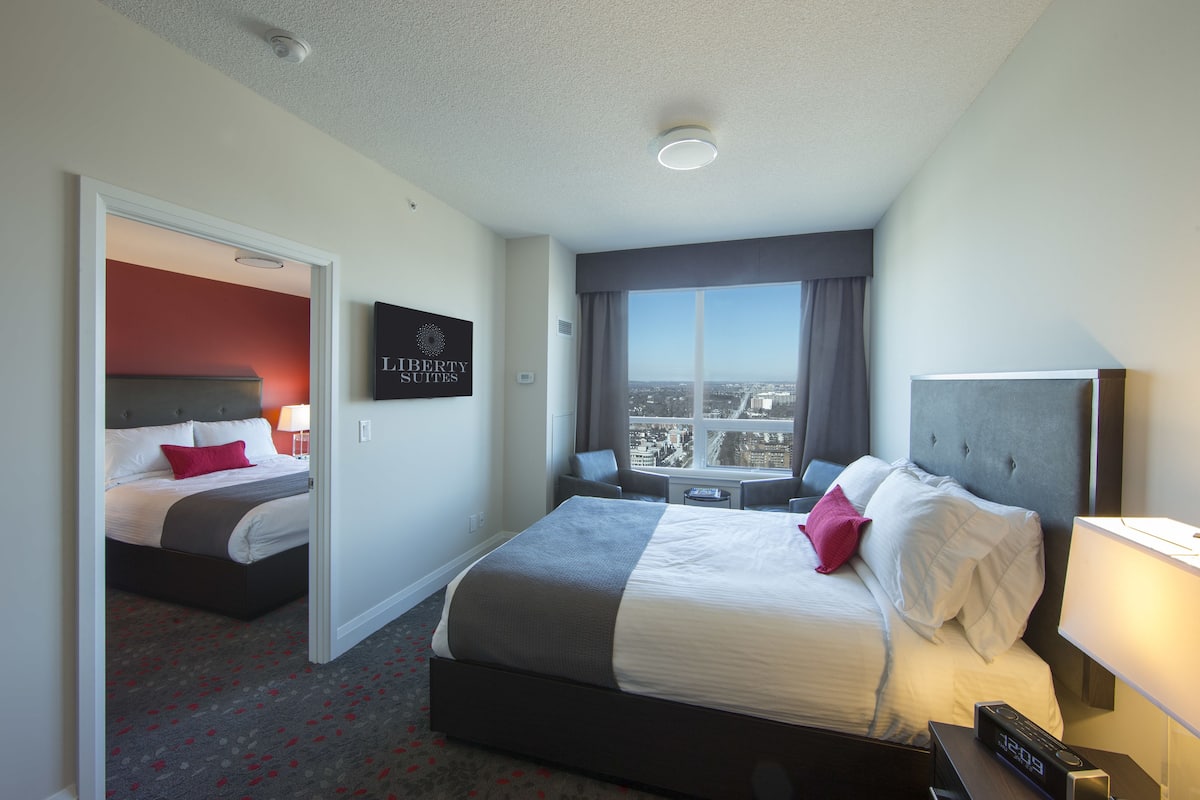 A hotel room with a large bed, a desk, and a view of the city.
