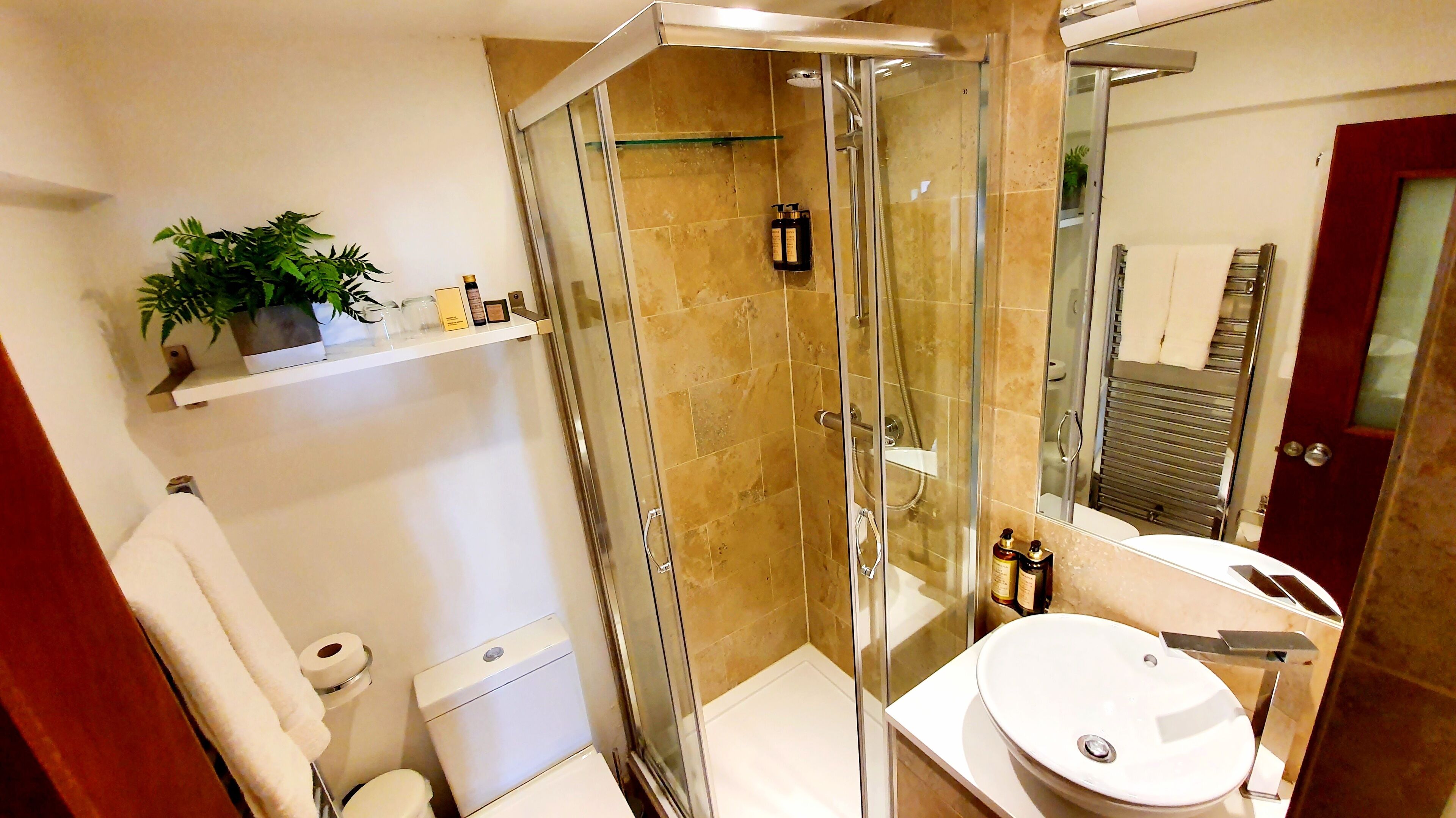 A modern bathroom with a glass-enclosed shower, a white toilet, and a sink with a mirror.