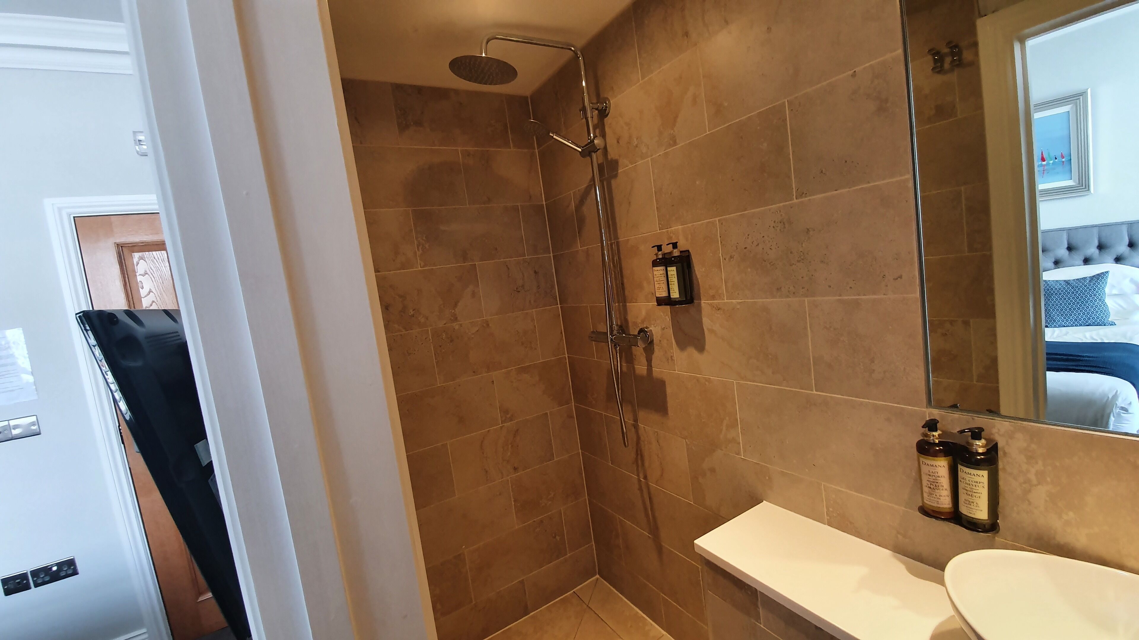 A bathroom with a shower, a toilet, and a sink. There is a mirror above the sink and a towel rack on the wall.