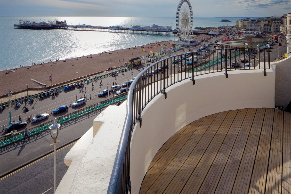 A seaside promenade with a Ferris wheel, beach, and promenade railing.