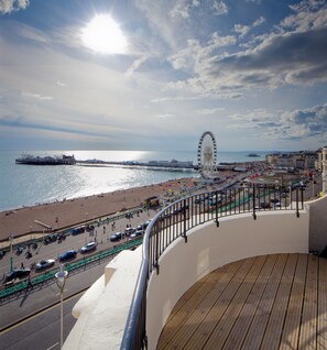Un paseo marítimo frente al mar, con noria, playa y barandilla.