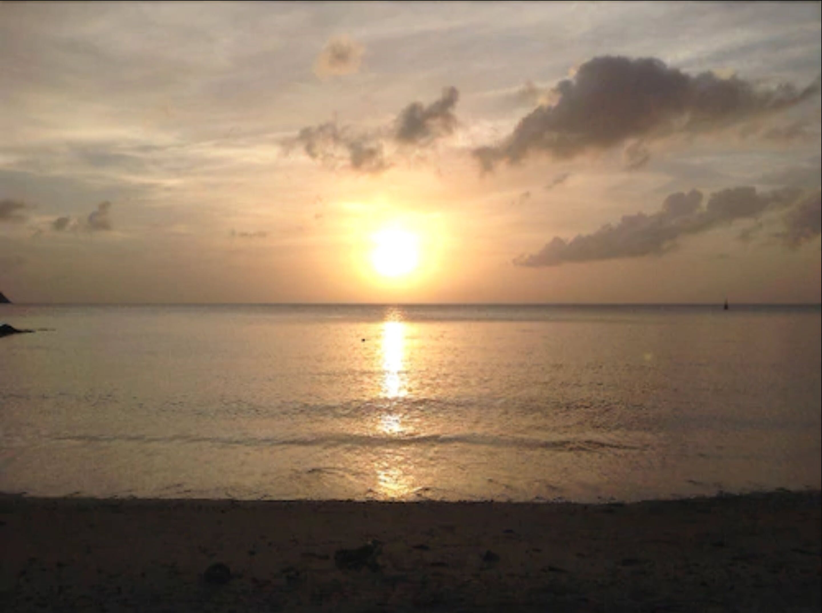 Un coucher de soleil sur une mer calme, avec une bouée visible au loin.