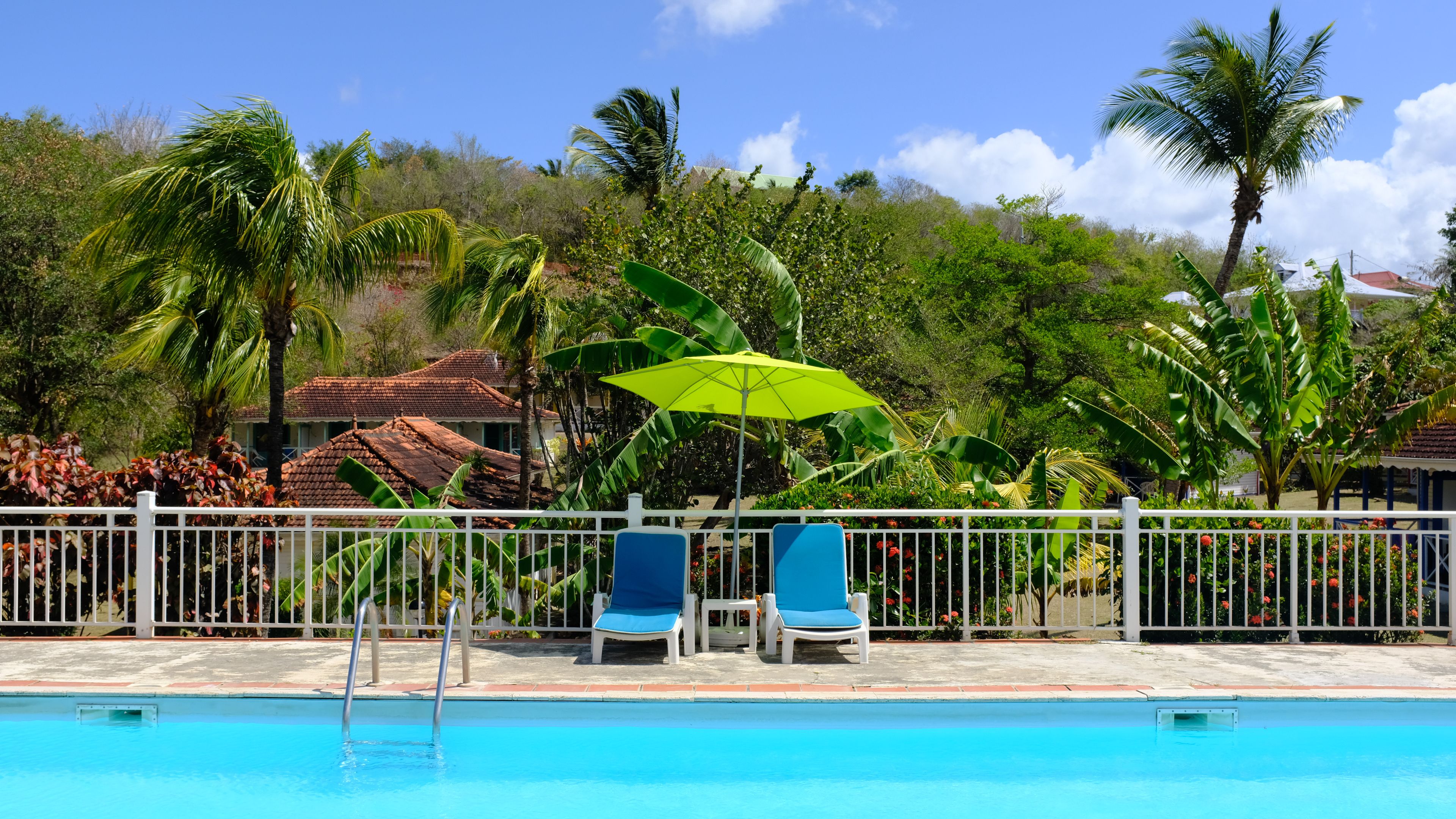 A swimming pool with two lounge chairs and a bright yellow umbrella.
