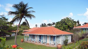 Un bâtiment bleu clair avec un toit rouge, entouré d’une végétation luxuriante et de palmiers.
