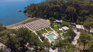 Vista aérea de un resort costero con una piscina grande, zona de playa y múltiples sombrillas.