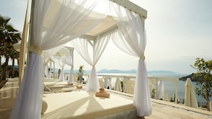 Un área de estar exterior lujosa con toldos blancos y vista al mar.