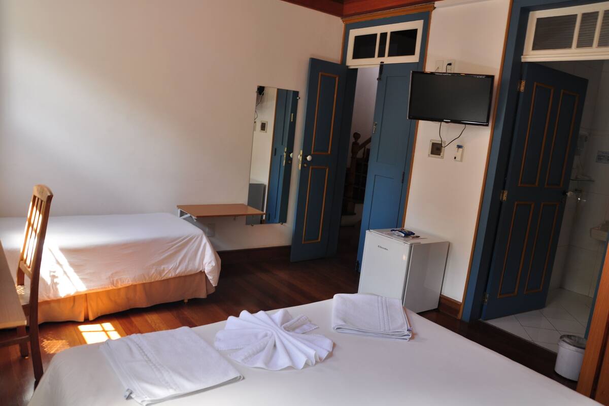 Een hotelkamer met twee bedden, een televisie, een bureau en een spiegel.