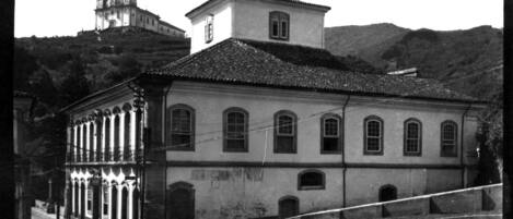 Un edificio histórico con tejado de baldosas, ventanas de arco y una torre de campanas.