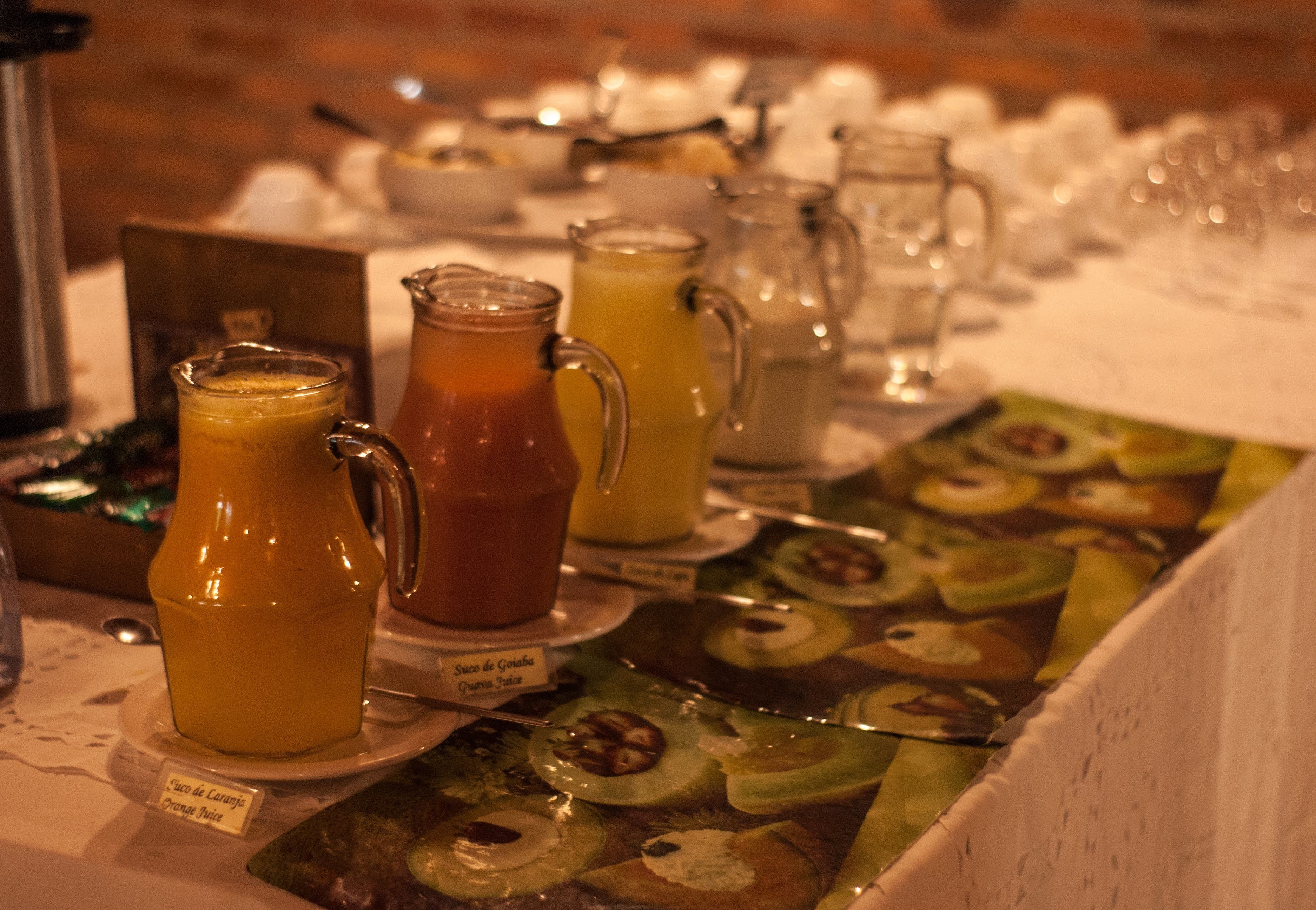 A breakfast buffet with various fruit juices and a fruit display.