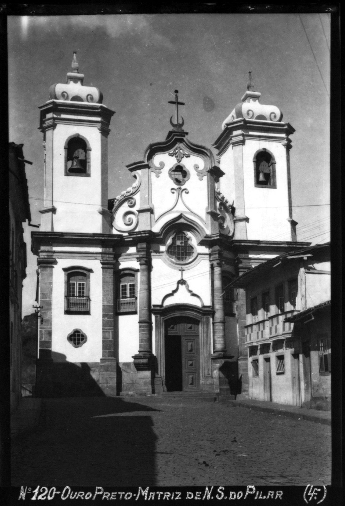 A historical building with two bell towers, a central entrance with an ornate design, and a cross above the main entrance.