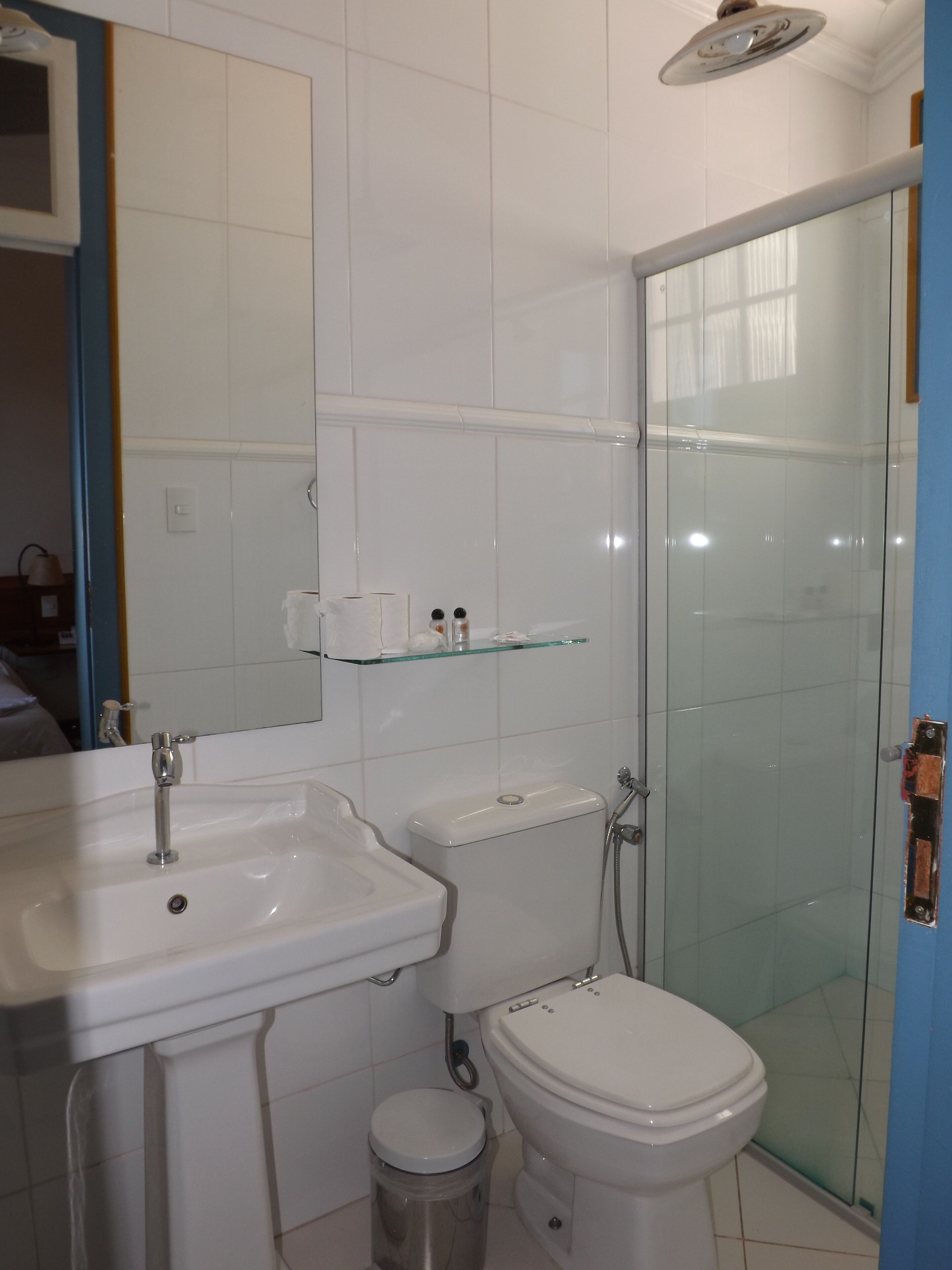 Casa de banho com lavatório, sanita e cabine de duche com vidro.
