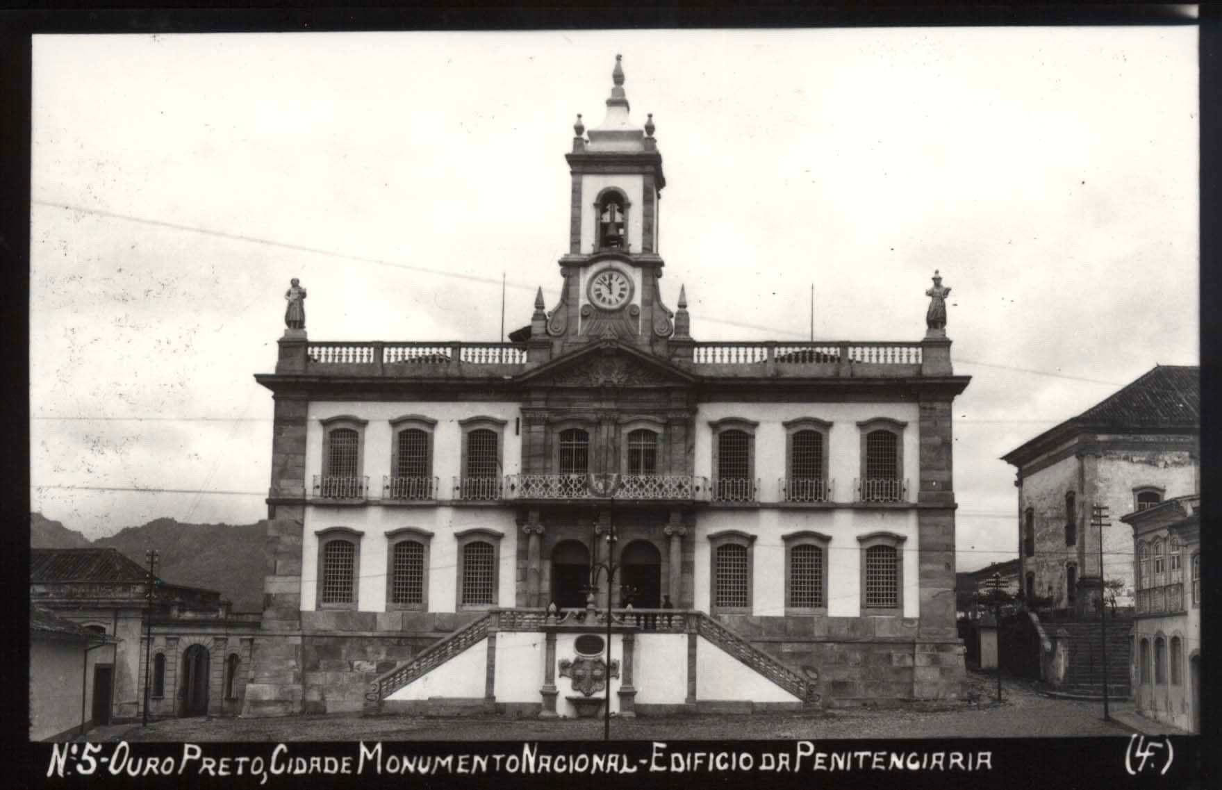 Un edificio storico con una torre dell'orologio, numerose finestre e un ingresso centrale con gradini.