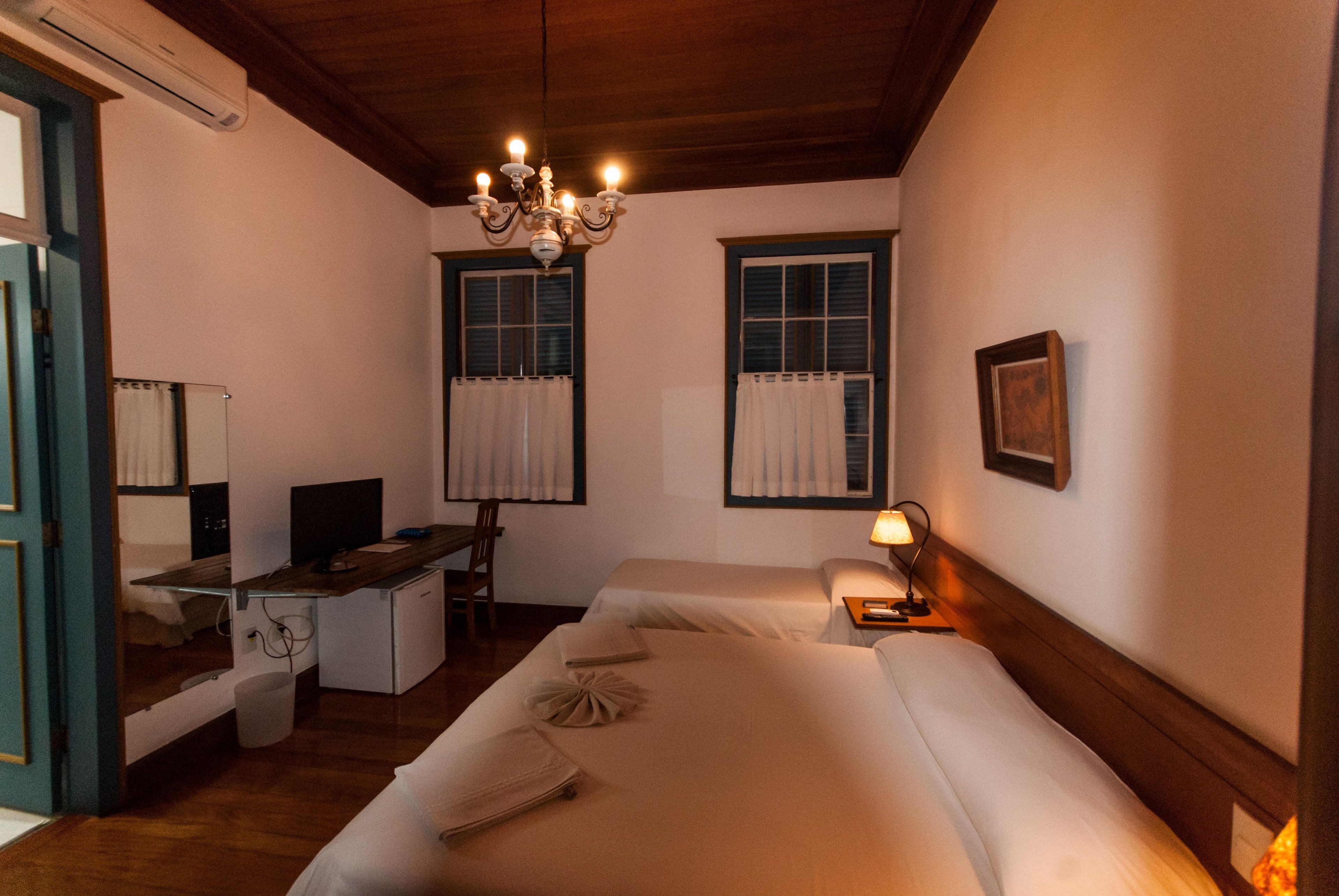 A hotel room with a bed, desk, chair, and a small kitchenette.