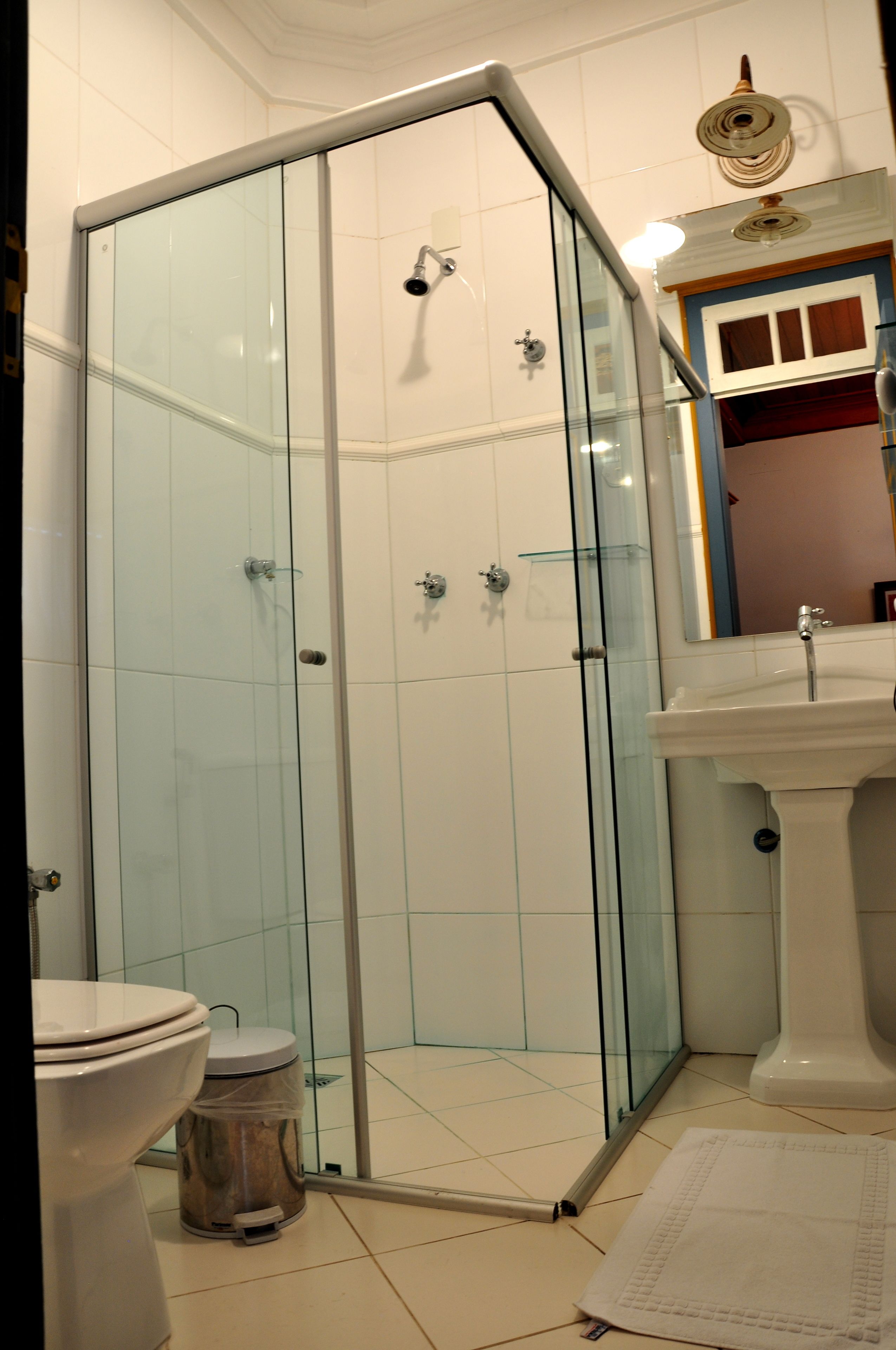 A bathroom with a glass-enclosed shower, a white sink, and a toilet.