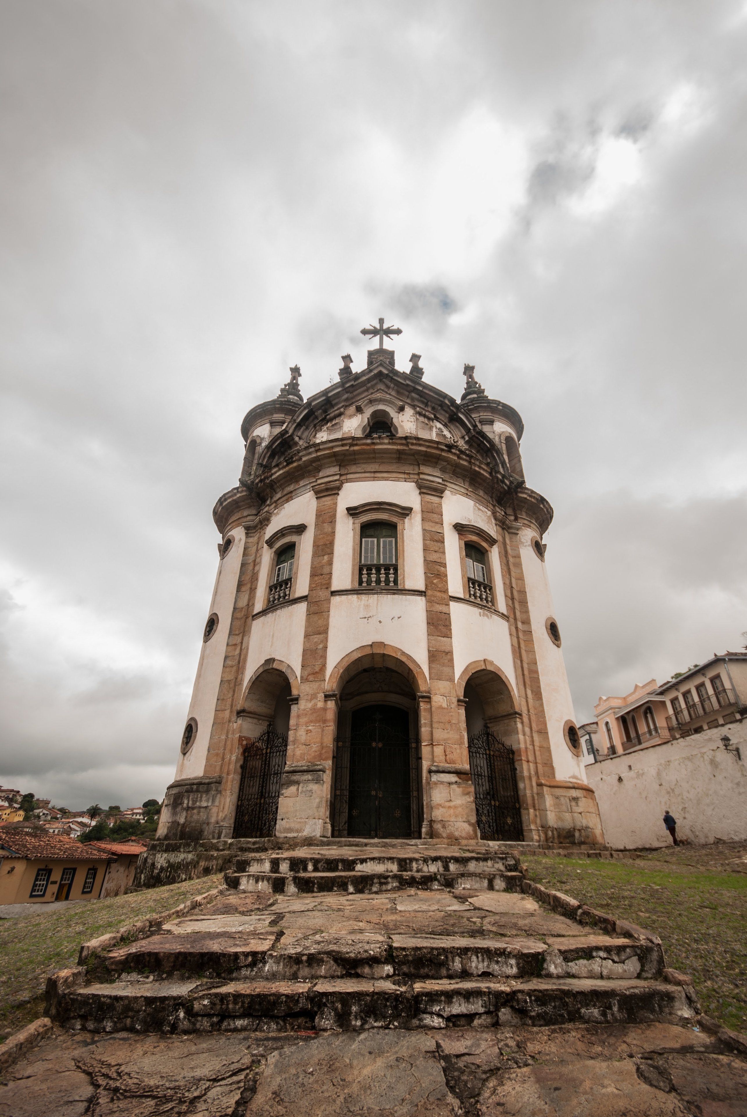 A historic building with a central dome, arched windows, and a staircase leading to the entrance.
