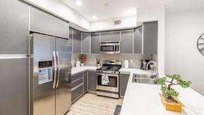 Una cocina moderna con electrodomésticos de acero inoxidable, microondas y pileta.