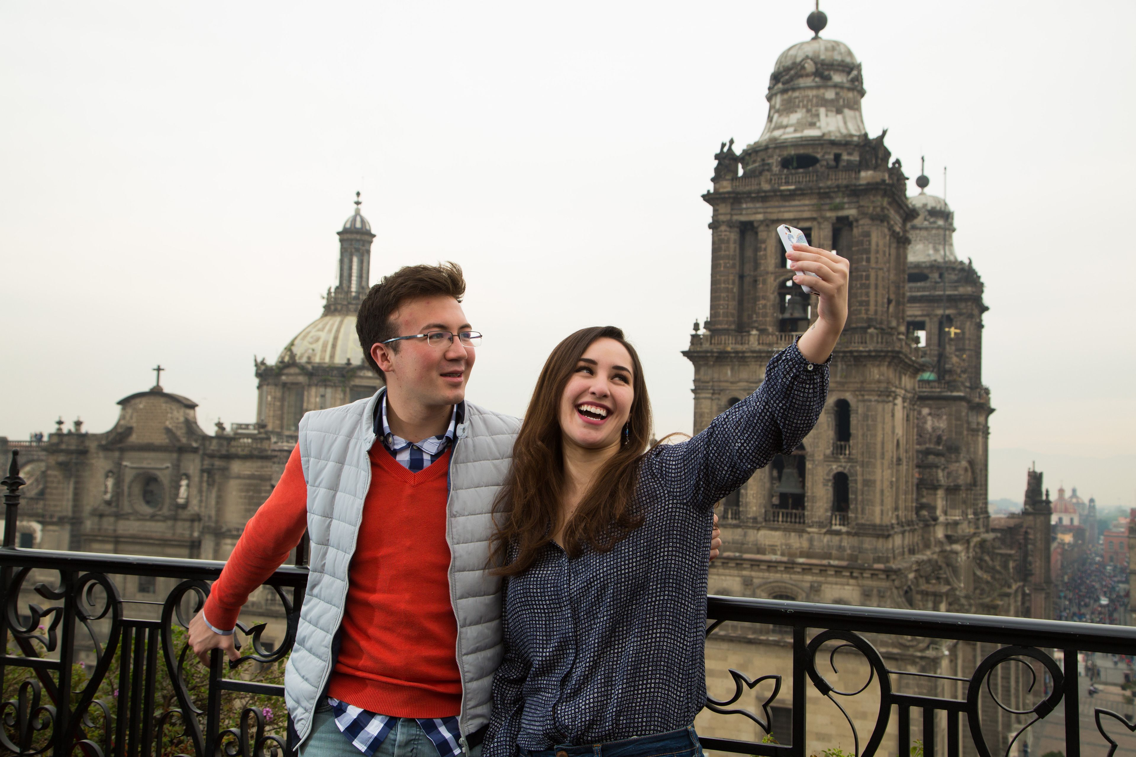 Una pareja se saca un selfie con un edificio histórico de fondo.