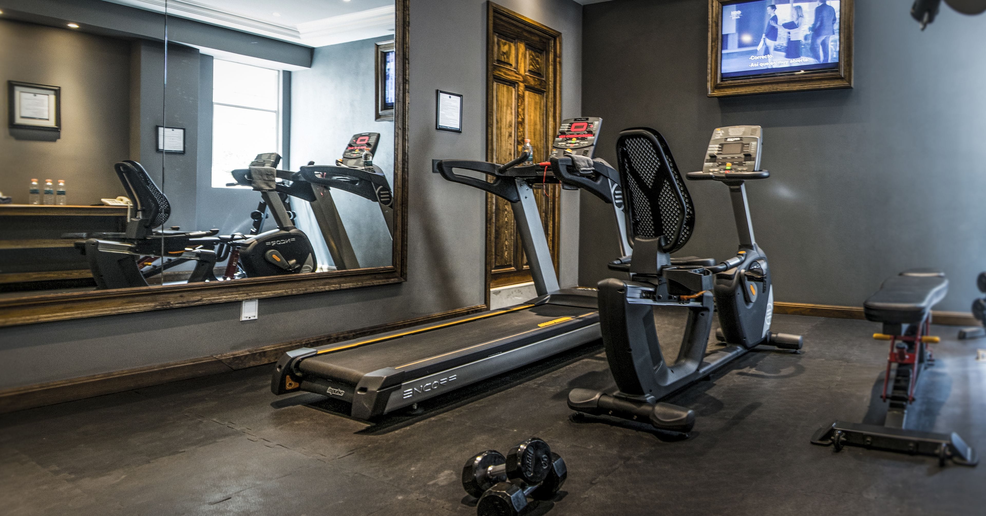 A gym with treadmills, an elliptical, and dumbbells.