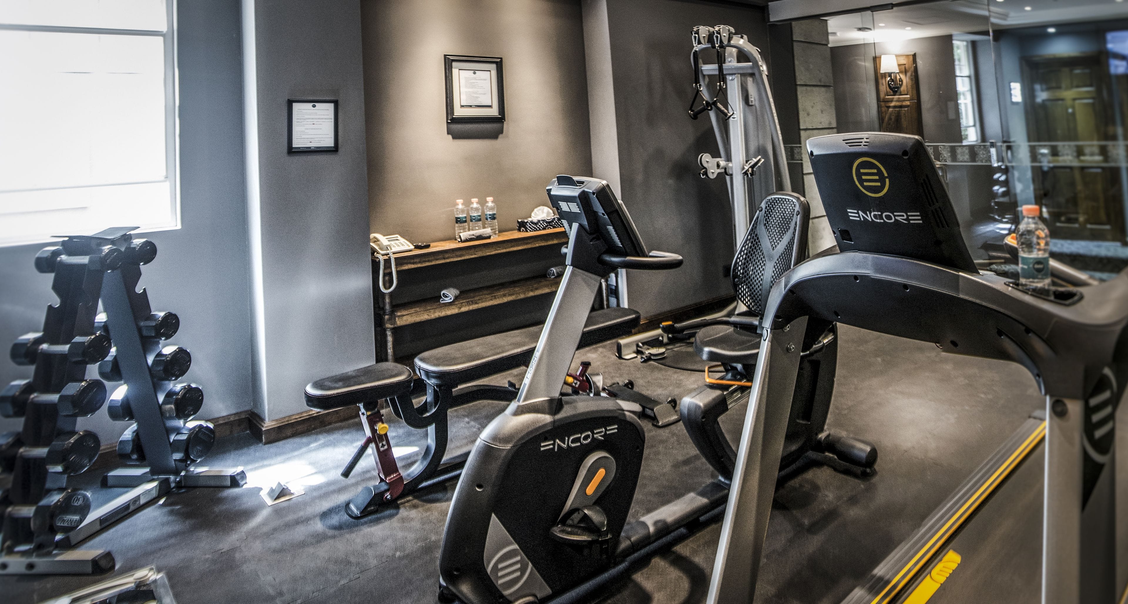 A gym with exercise equipment, a reception desk, and a water bottle on the counter.