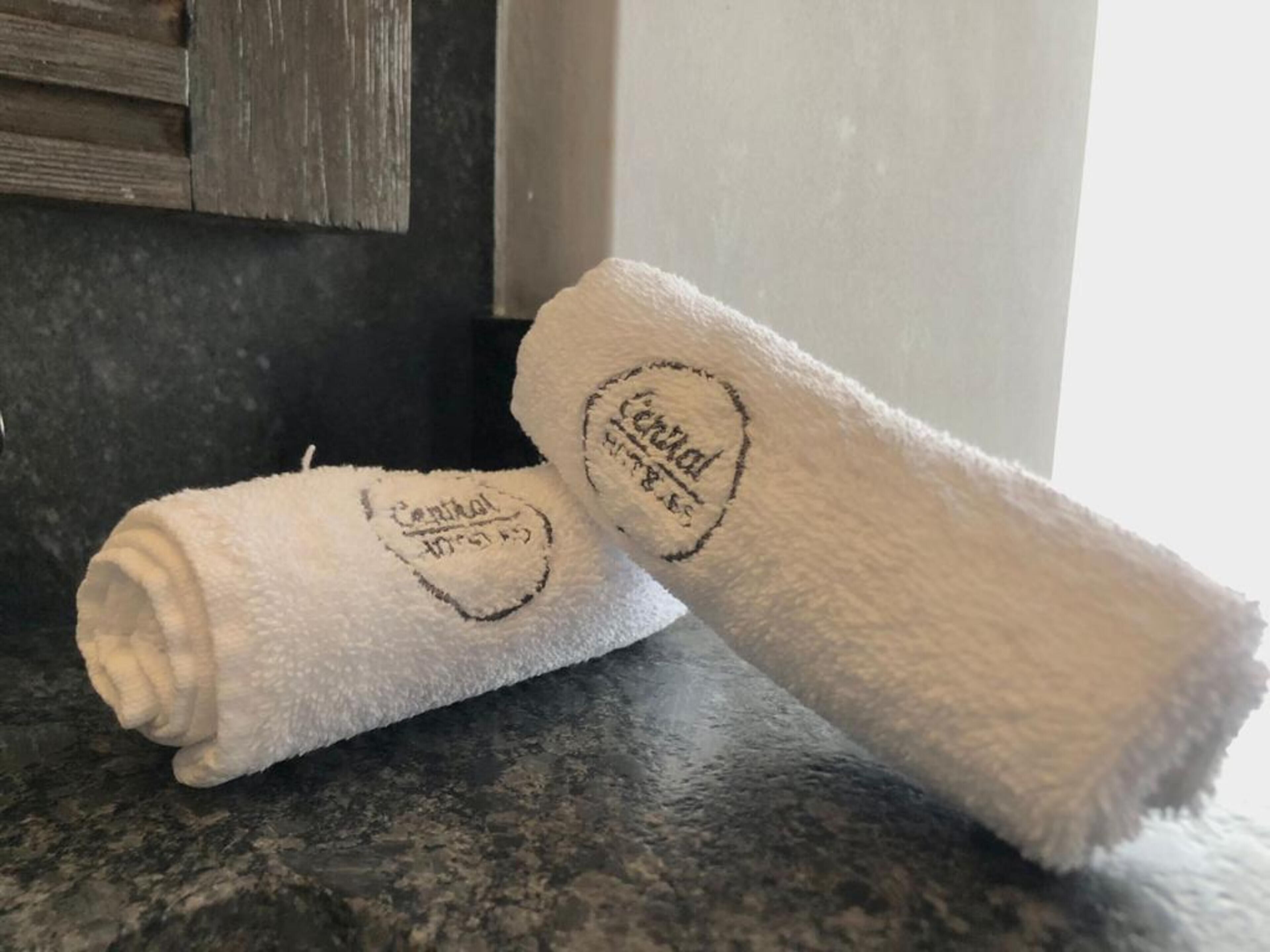 Two white towels with embroidered text on a dark countertop.