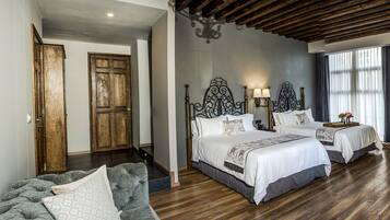 Habitación de hotel con dos camas, techo de madera, un espejo grande y un escritorio con un jarrón de flores.