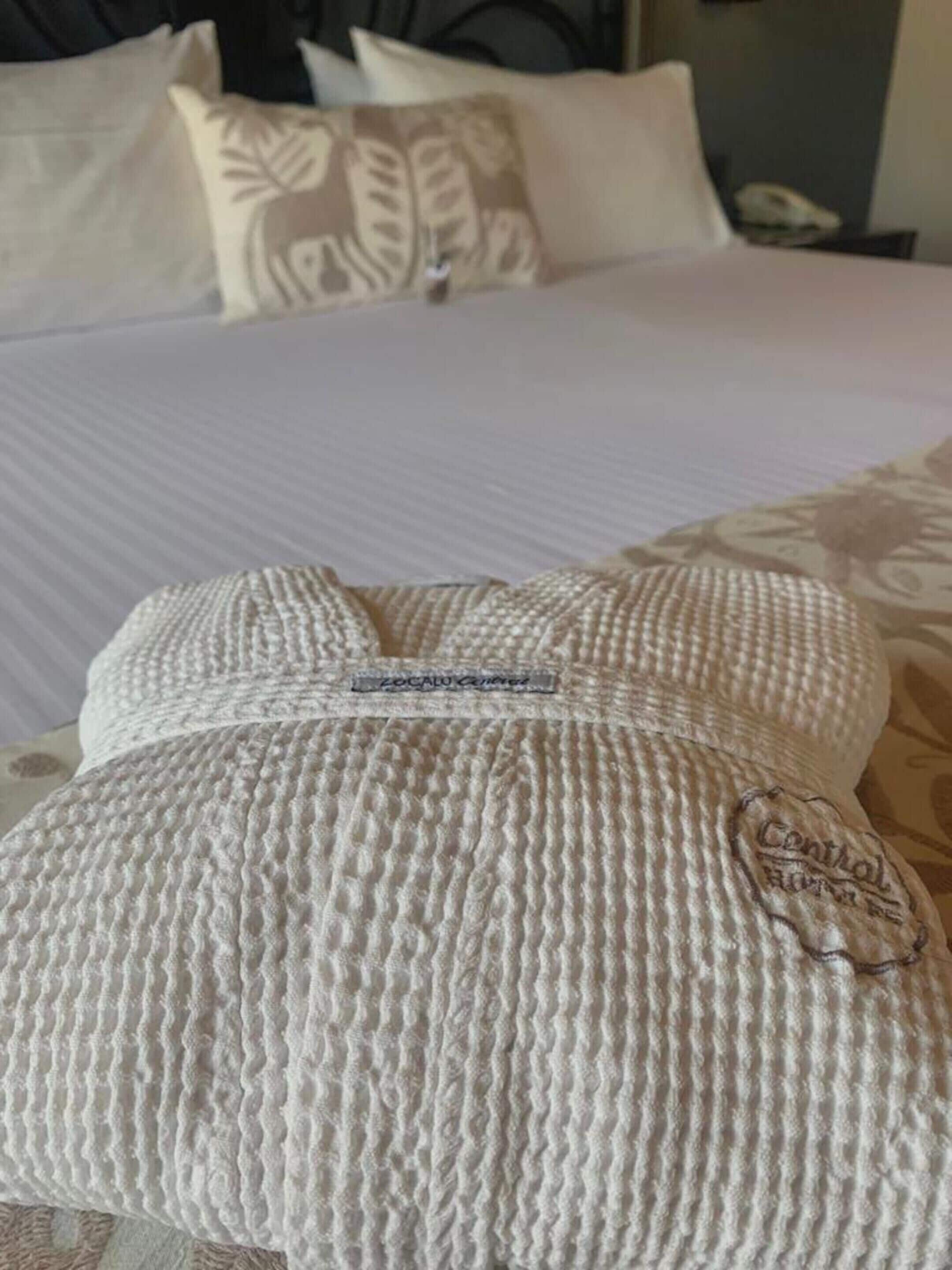 Cama com roupa de cama branca e almofada com padrão de tricô.