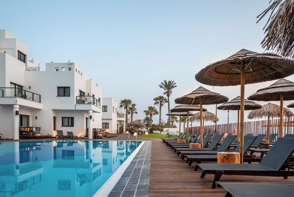 A swimming pool with lounge chairs and umbrellas, surrounded by modern buildings. - Sea life Nahariya BY Jacob Hotels (Nahariya)
