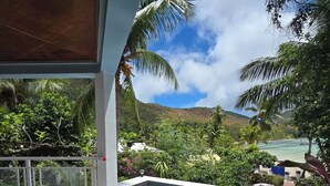 A poolside area with a view of a lush landscape and a mountain in the background. - Sea View Lodge (Praslin Island)