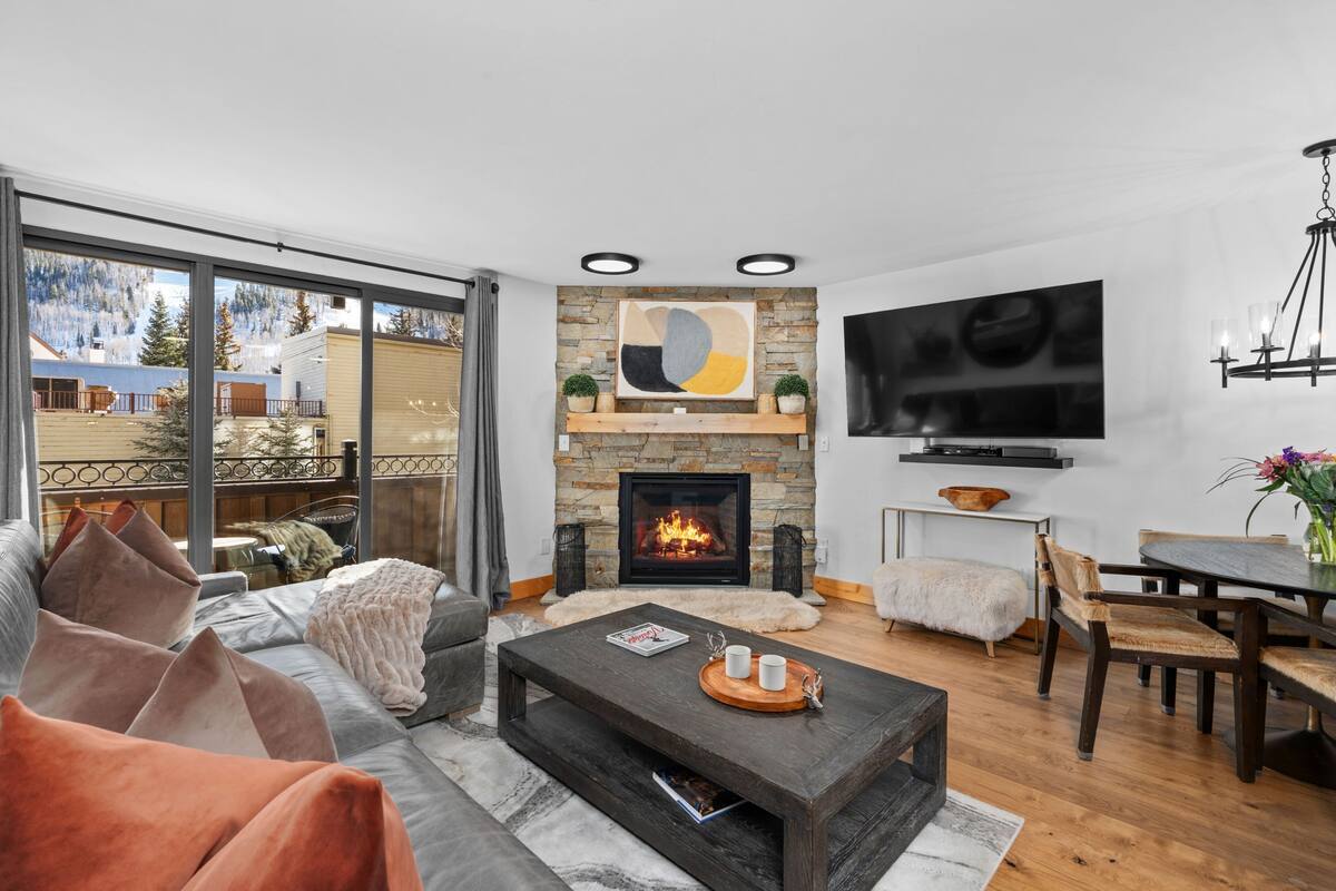 A modern living room with a fireplace, large TV, and comfortable seating.