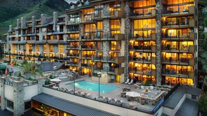 A multi-story hotel with balconies, a pool, and a mountainous backdrop. - The Landmark (Vail)