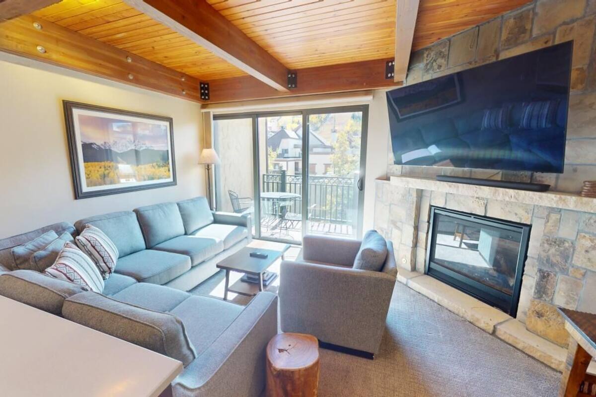 A cozy living room with a stone fireplace, a large flat-screen TV, and a comfortable seating area.