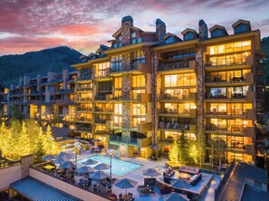 A multi-story hotel with balconies, a swimming pool, and outdoor seating areas. - The Landmark (Vail)