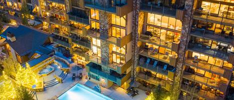 A multi-story hotel with outdoor swimming pool, sun loungers, and a fire pit area.
