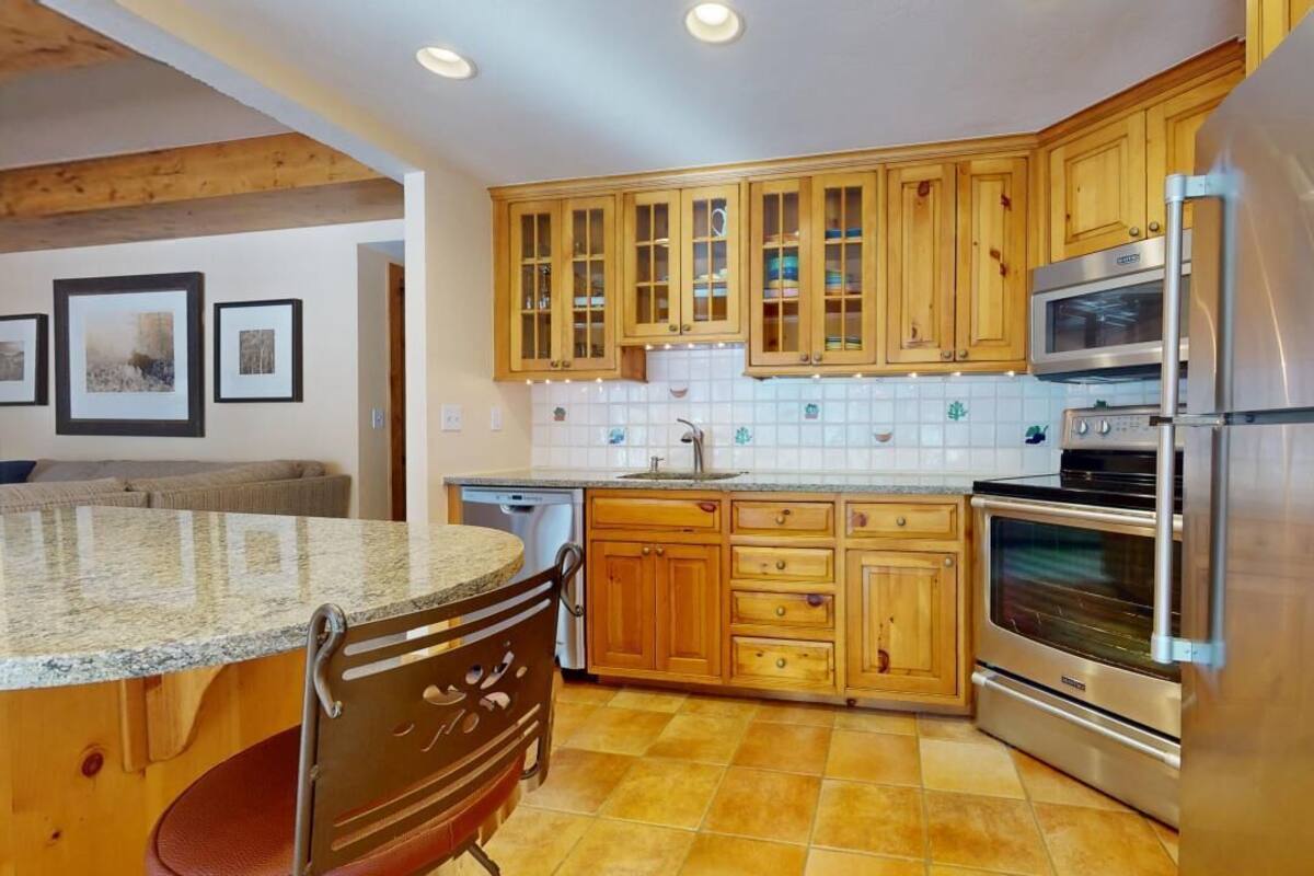 A kitchen with wooden cabinets, a stainless steel refrigerator, and a built-in oven.