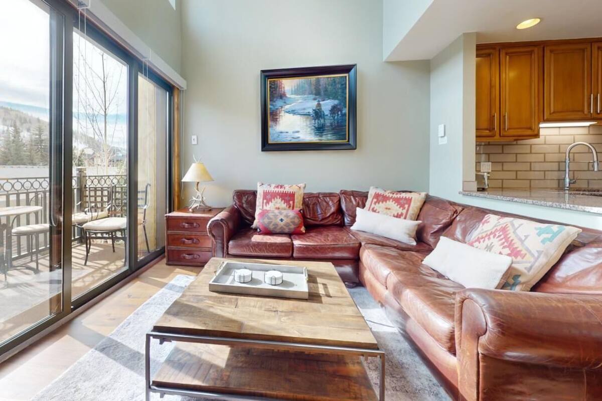 A living room with a leather sofa, a coffee table, and a painting on the wall.