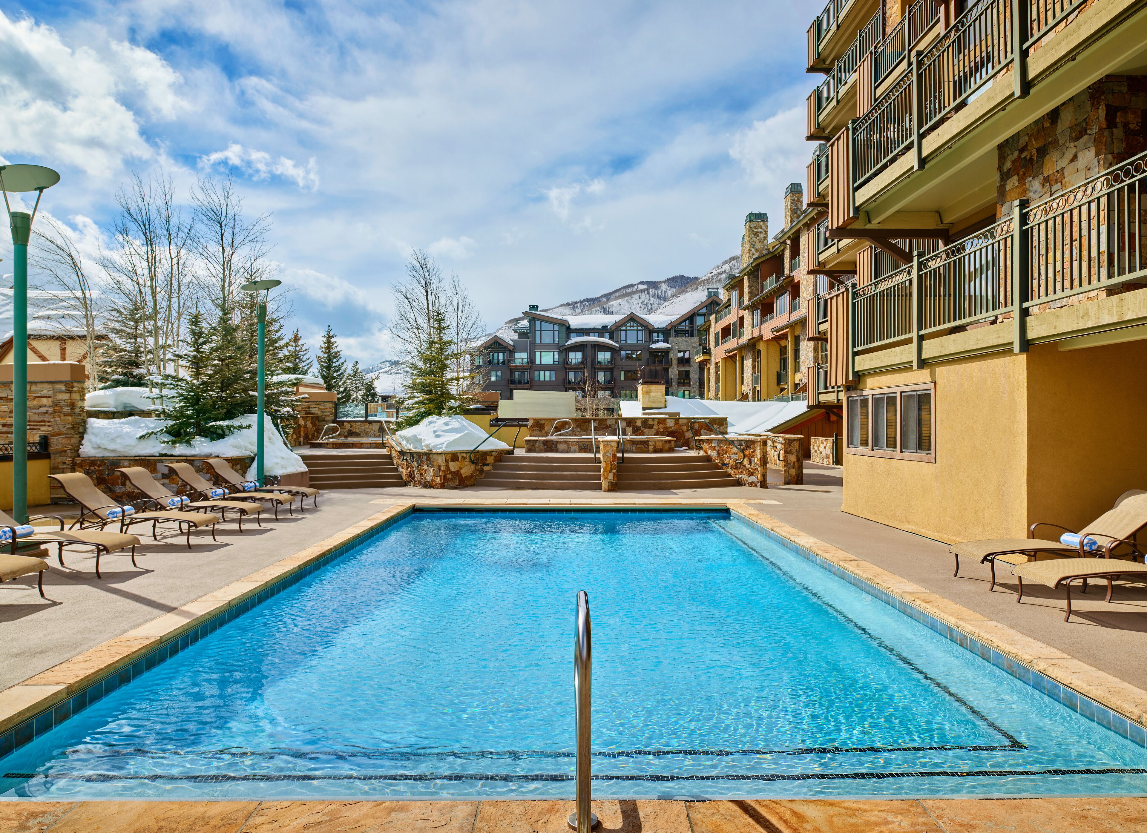 A pool area with lounge chairs and a view of a mountain.