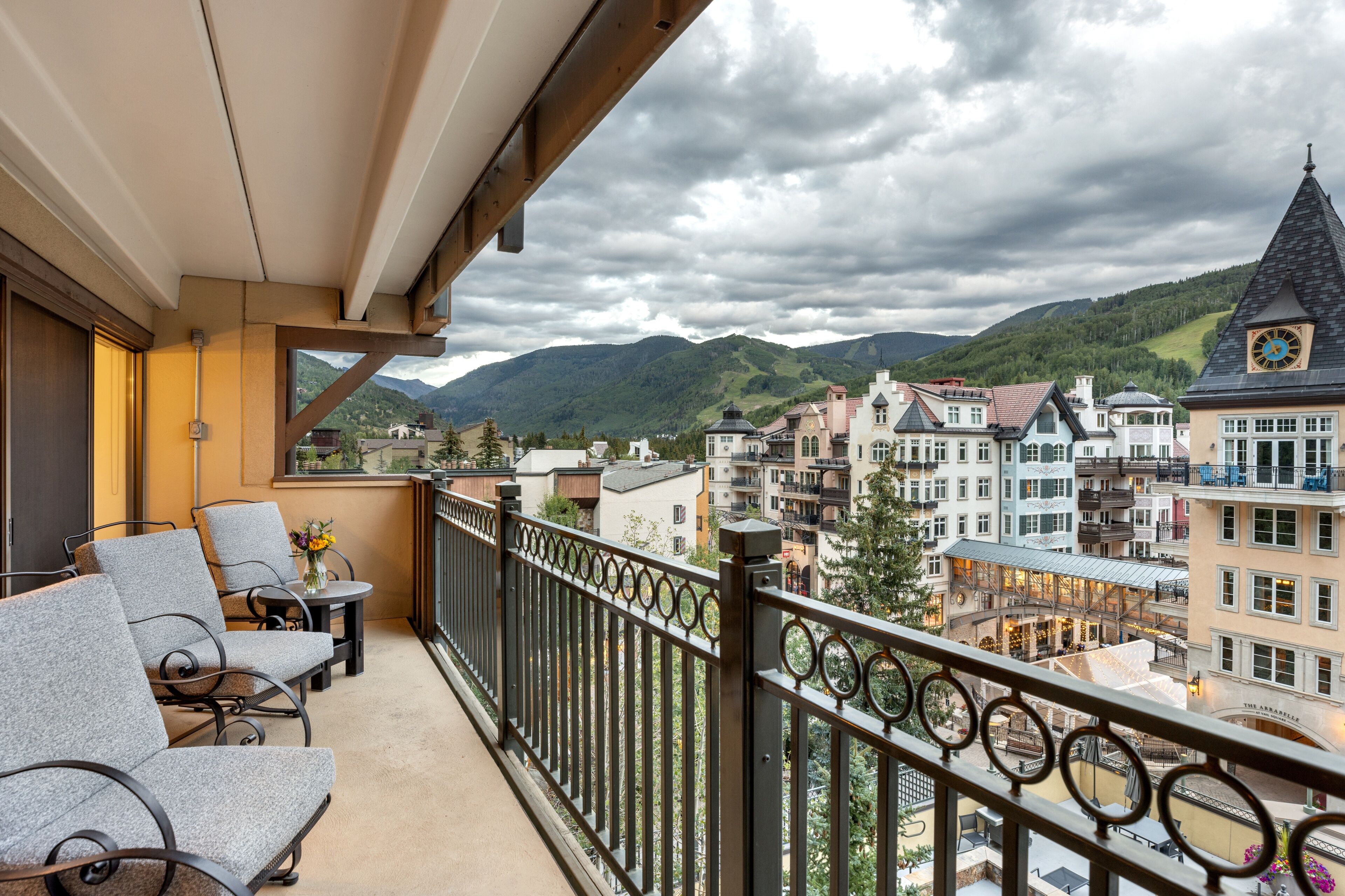 Ein Balkon mit Sitzgelegenheit und Blick auf eine Stadt mit historischen Gebäuden und Bergen.