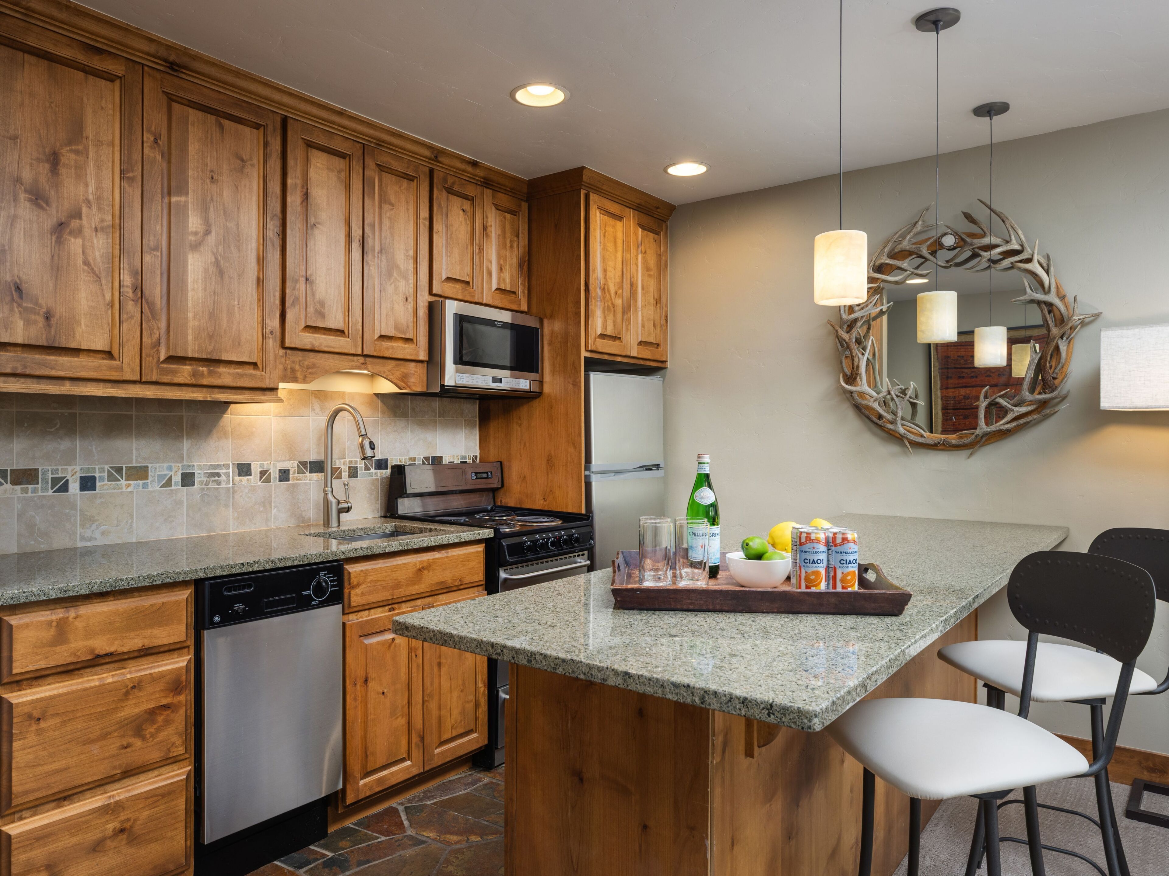 A kitchen with wooden cabinets, a microwave, a stove, and a bar area with chairs.