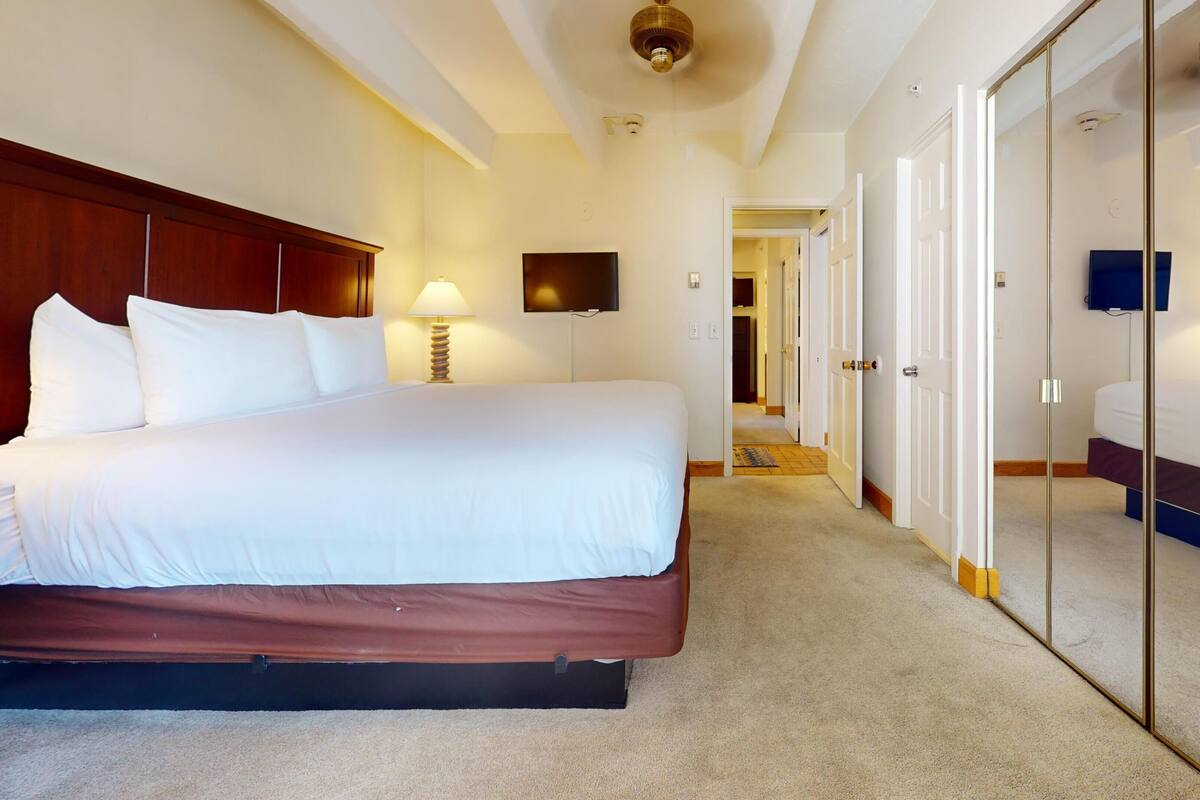 A hotel room with a large bed, bedside lamps, a flat-screen TV, and a walk-in closet.
