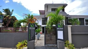 A West Palm Beach Inn entrance with a modern design, featuring a gated driveway, potted plants, and a clear sky. - West Palm B&B Inn (Flic-en-Flac)