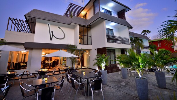 A modern building with outdoor seating and potted plants. - West Palm B&B Inn (Flic-en-Flac)