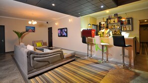 A modern living room with a sofa, a TV, and a bar area with stools and a counter. - West Palm B&B Inn (Flic-en-Flac)