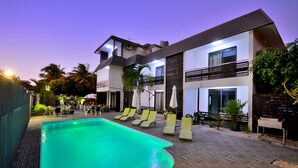 A modern two-story building with a swimming pool, lounge chairs, and a well-maintained garden. - West Palm B&B Inn (Flic-en-Flac)