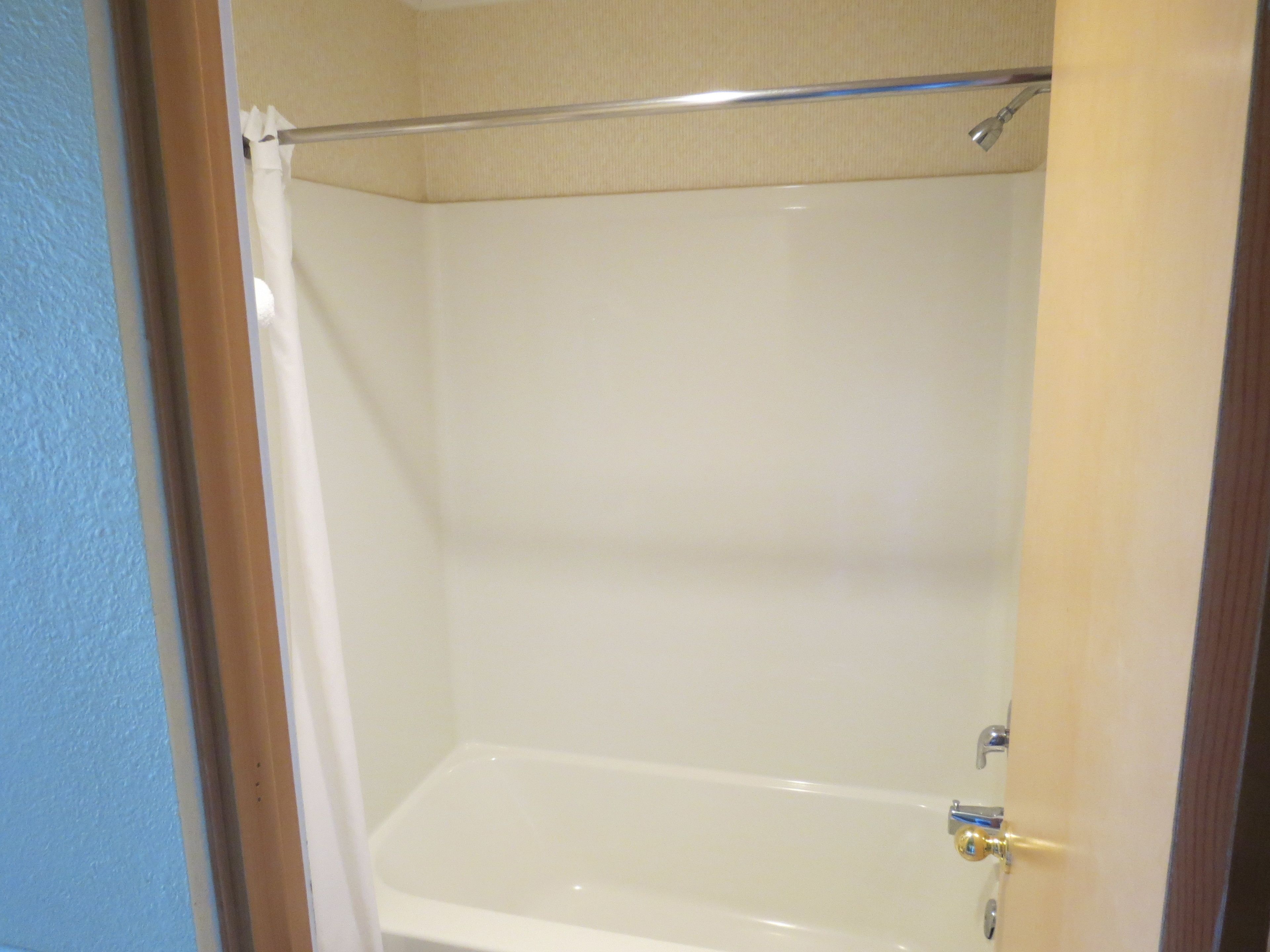 A bathroom with a bathtub, a shower curtain, and a showerhead.