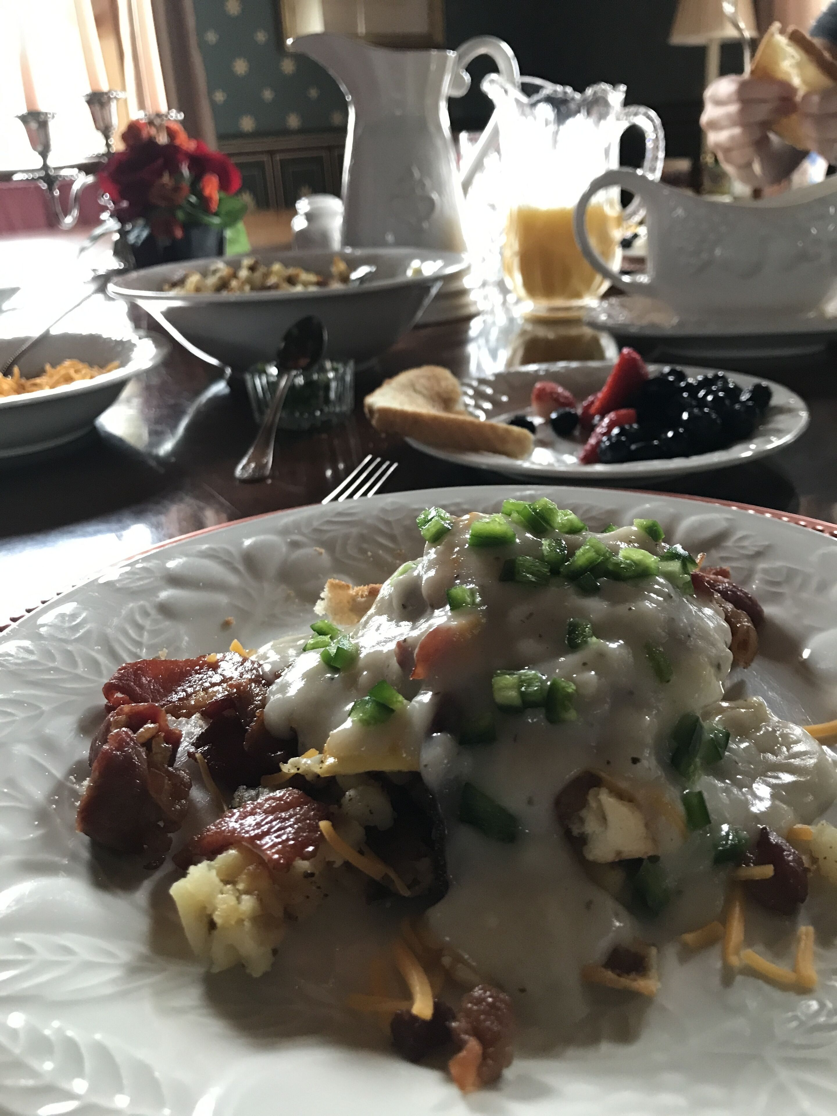 A dining table with various dishes, including a plate with a creamy sauce and green toppings, a pitcher, and other plates with food.