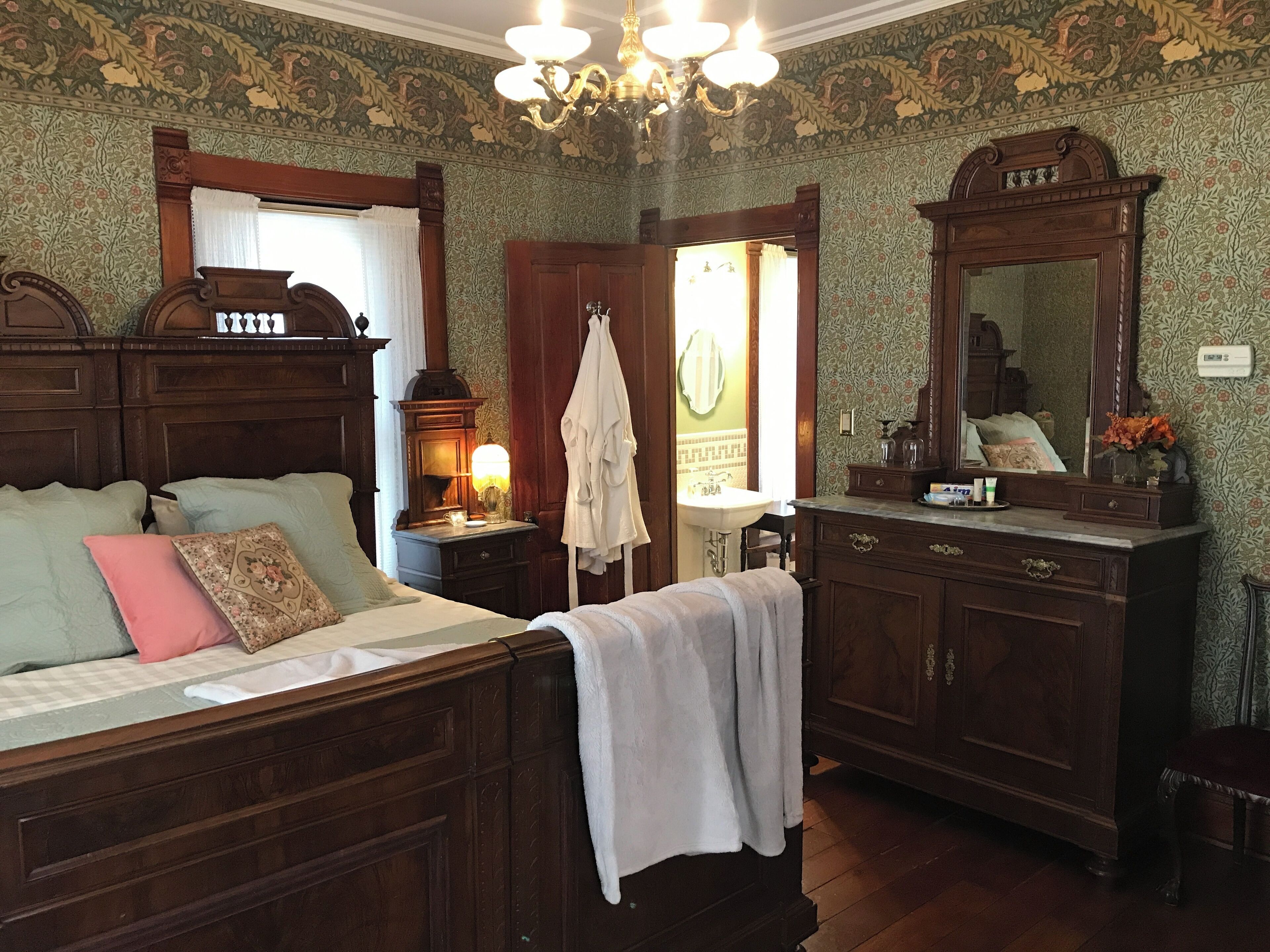Une chambre à coucher de style traditionnel, avec un lit en bois, une table de chevet avec une lampe, une commode et un miroir.