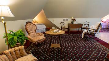 A cozy room with a bed, a chair, a table, and a lamp.