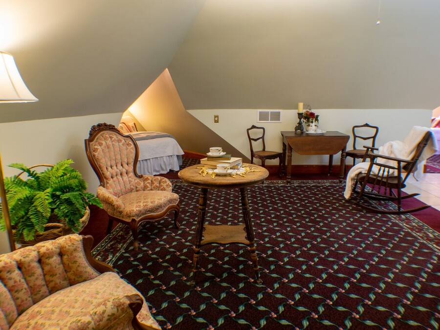 A cozy room with a bed, a chair, a table, and a lamp.